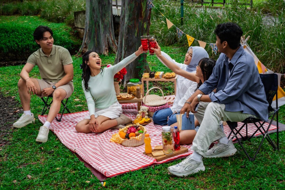 Offres A cheerful group of friends enjoying a vibrant picnic in a lush garden setting in Indonesia.