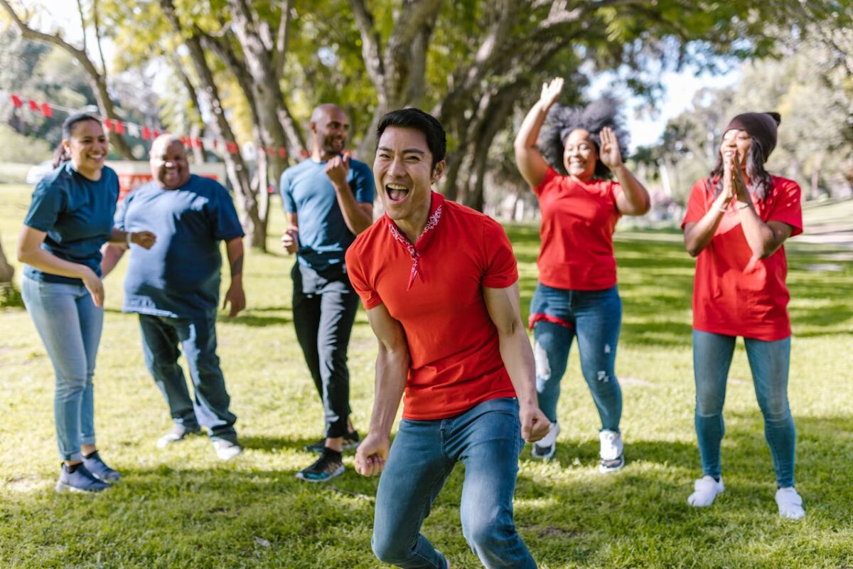 Group of happy adults playing and bonding in a park during a fun team building event.